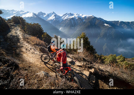 Mountain bikers take a rest on an Enduro style single track trail in the Nepal Himalayas near the Langtang region, Nepal, Asia Stock Photo