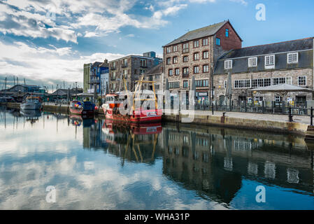 Fishing boats moored at Sutton harbour, with shops and cafes on the quayside, The Barbican, Plymouth, Devon, England, United Kingdom, Europe Stock Photo