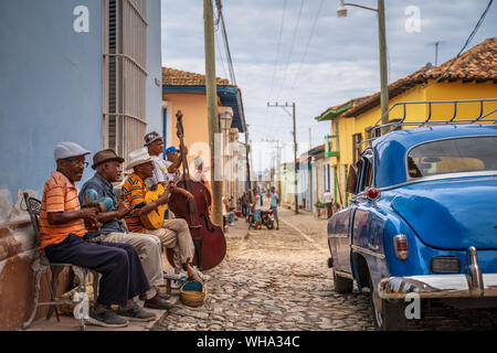 Elderly Cubans playing music on the street, American classic car, Trinidad, Sancti Spiritus Province, Cuba, West Indies, Caribbean, Central America Stock Photo