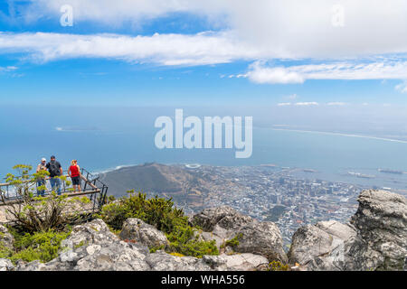 Tourists at a viewpoint on Table Mountain looking west over the city and ocean, Cape Town, Western Cape, South Africa Stock Photo