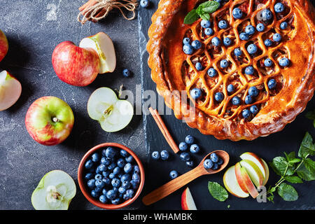 Apple Blueberry Pie on a black slate plate on a concrete table with ingredients, view from above, flatlay Stock Photo