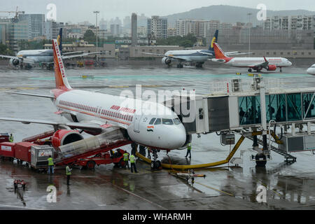 INDIA, Mumbai , Chatrapati Shivaji International Airport, Airbus of Air India, ground staff service team and boarding passenger on boarding bridge, behind Mumbai skyline and aircraft of private airline Jet Airways which went in insolvency in 2019 Stock Photo