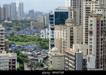 INDIA, Mumbai, city growth, skyscraper with expensive apartments and slum huts of slum dweller beside in suburb Goregoan, society contrast rich and poor, wealth and poverty, plot of land, property Stock Photo