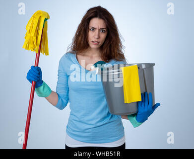 Young beautiful upset housewife woman holding bucket mop cleaning spray feeling stressed tired and frustrated in domestic duties and gender roles conc Stock Photo