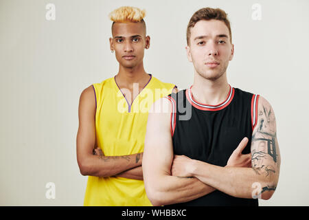Studio portrait of confident multi-ethnic basketball team players standing one behind another and looking at camera Stock Photo