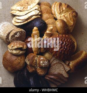 A display of different types of bread including pitta , wholemeal , sliced loaf , roll , sesame seed , knotted . Stock Photo