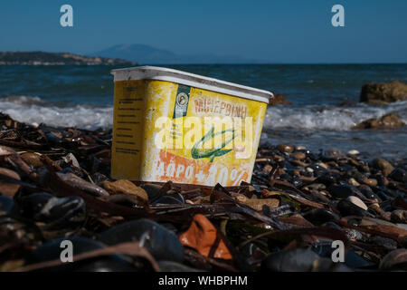 A plastic Sweetcorn container discarded on the beach with water fading and damage adding to the now pollution of the ocean and environment damage. Stock Photo