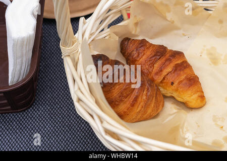 Two fresh croissants in a wicker basket. French croissants. Stock Photo