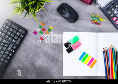 The layout of school supplies on a dark gray background. Top view, the sun's rays from the side. Back to school. Flat lay Stock Photo