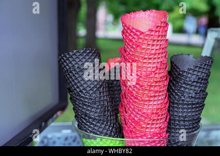 Wafer cups for ice cream of red and black colors. Waffle cones on the counter of an ice cream seller. Stock Photo