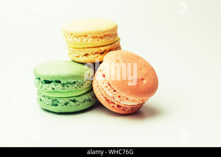 three fresh colored macaroons lie in a heap in the center. Meringue on an isolated background with copy space Stock Photo