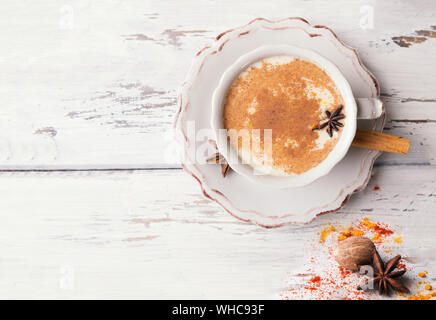 Beautiful cup of traditional indian masala chai tea on with star anise and cinnamon on a shabby wooden texture background, top view. Ingredients: cinn Stock Photo