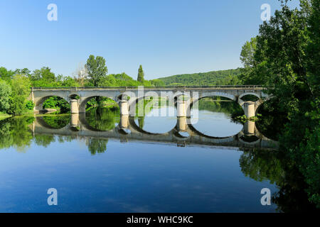 Multi-arched stone bridge over quiet river in France with man fishing from rowing boat. Stock Photo