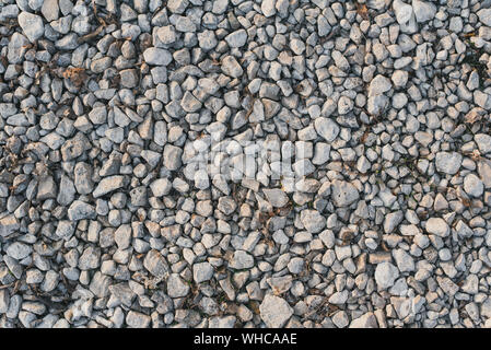 A lot of small pebbles lies on a path in the park. Preparing the road for leveling. Stone background. Stock Photo