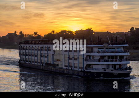 Big cruise in sunset, in Nile river in Egypt between Luxor to Aswan. At background a egyptian village Stock Photo