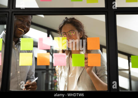 Two diverse happy team people working together with sticky notes Stock Photo