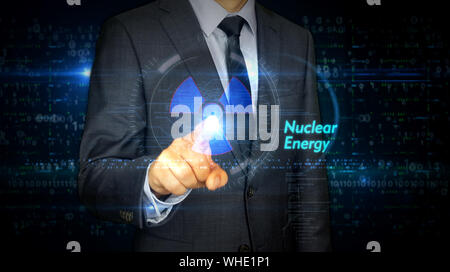 A businessman in a suit touch screen with nuclear energy symbol hologram. Man using hand on virtual display interface. Science, danger icon and cyber Stock Photo
