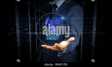 A businessman in a suit touch screen with nuclear energy symbol hologram. Man using hand on virtual display interface. Science, danger icon and cyber Stock Photo
