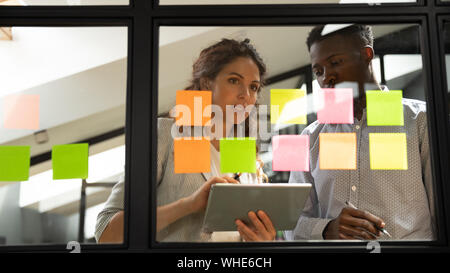 Two serious coworkers checking project plan writing on sticky notes Stock Photo