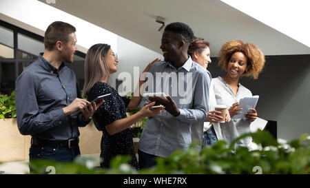 Happy friendly multiethnic business team talking laughing standing in office Stock Photo