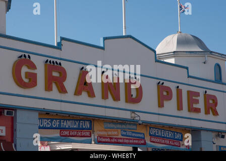 Starlings perched on the G and the R of the pier name sigh, the Grand Pier, Weston-Super-Mare, Somerset, England UK Stock Photo