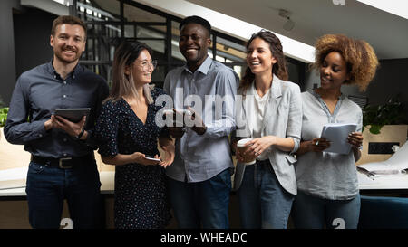 Cheerful happy multicultural business team laughing standing in office Stock Photo