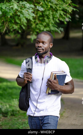 Motivated young African male student going to classes through campus park Stock Photo