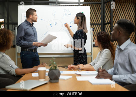 Diverse asian and caucasian coaches drawing on whiteboard in office Stock Photo