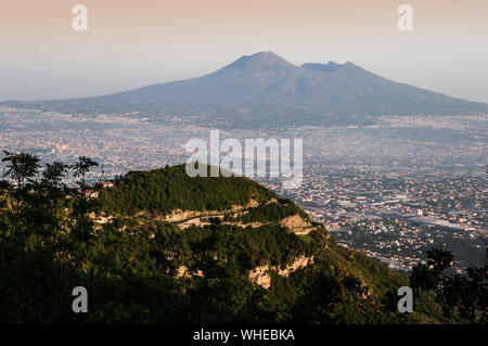 Mount Vesuvious photographed from near Ravello on a hazy summer morning. The urban sprawl of Salermo and parts of Naples can be seen in the middle of Stock Photo