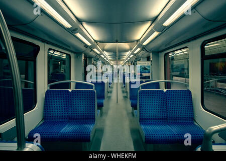 Hamburg, Germany - May 22, 2018: empty seats of modern high speed commuter metro train, night lights turned on. Stock Photo