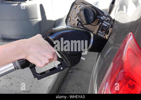 A hand is shown operating a gas pump nozzle at a filling station, in an up close view. Stock Photo