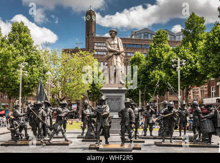 Amsterdam, the Netherlands - July 1, 2019: De Nachtwacht compostion of statues on Rembrandtplein in front of beige tall statue of Rembrandt Van Rijn, Stock Photo