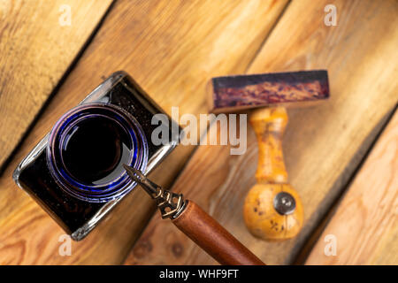 Old stylish calligraphy nib, ink and stamp on a wooden table. Writing accessories prepared for work. Dark background. Stock Photo