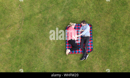 Aerial view of a pregnant woman and partner relaxing in a park Stock Photo