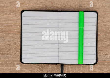 Open notebook with green marker on desk Stock Photo