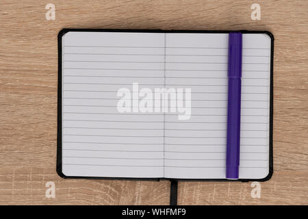 Blue marker and open notepad on desk Stock Photo