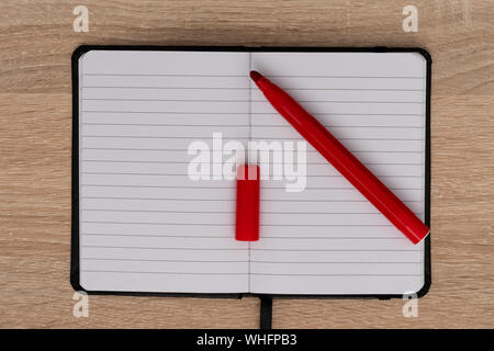 Red pen on open notepad on wooden desk Stock Photo
