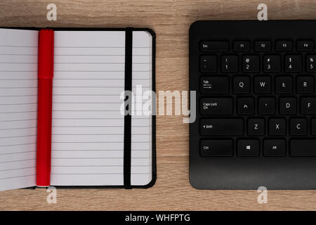 Pen on open notebook with black keyboard Stock Photo
