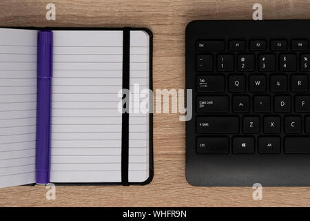 Blue pen on open notepad with keyboard Stock Photo
