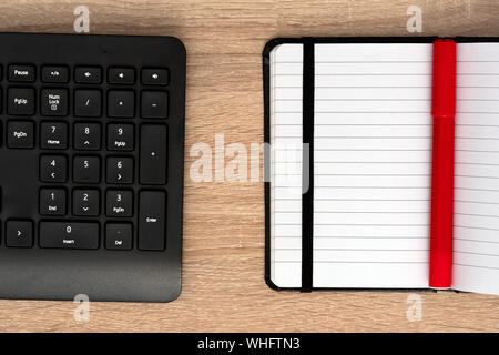 Red pen on notepad with black keyboard Stock Photo