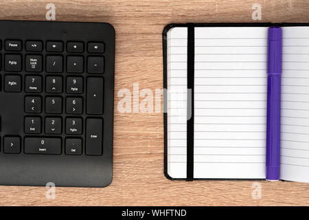 Blue marker on open notepad and keyboard Stock Photo