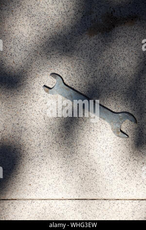 An old rusty double open end wrench lies on the tiled floor in sun glare Stock Photo