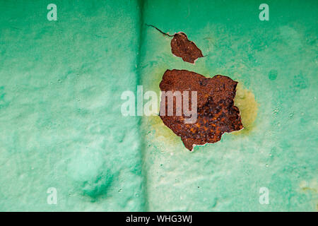 Green painted iron with rusty patches showing through Stock Photo