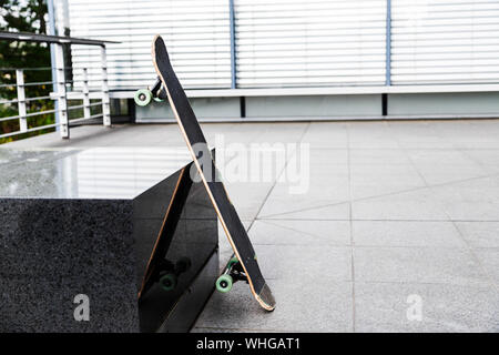 Skateboard leaned against granite stand on street Stock Photo