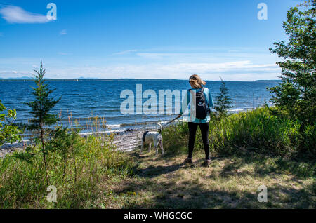 female hiker with dog walking next to lake Stock Photo
