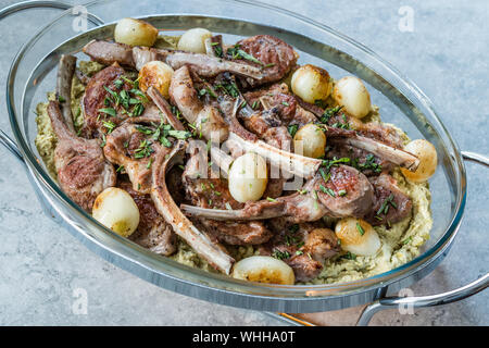 Lamb Chops with Shallots, Green Pea Hummus and Fresh Thyme Leaves served in Big Glass Tray Plate. Organic Meat Food. Stock Photo