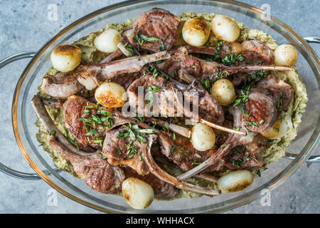 Lamb Chops with Shallots, Green Pea Hummus and Fresh Thyme Leaves served in Big Glass Tray Plate. Organic Meat Food. Stock Photo