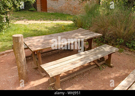 A rustic picnic table and bench in a playground Stock Photo