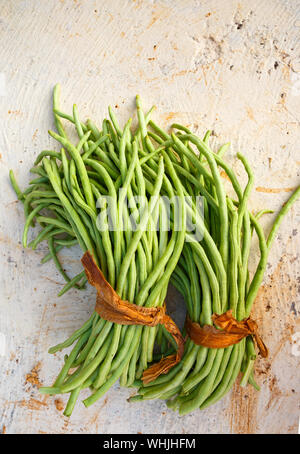 Overhead view of two bunches of Cuban green beans on a white concrete surface Stock Photo