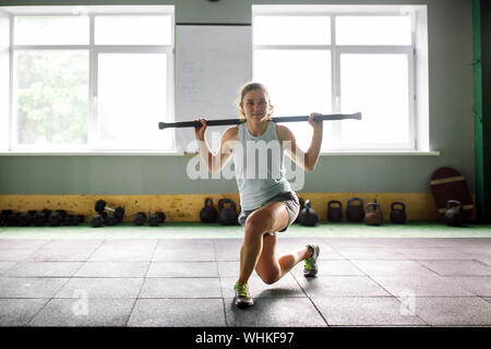 beautiful young woman doing sit-up exercises with a weight stick on the buttocks in the gym Stock Photo